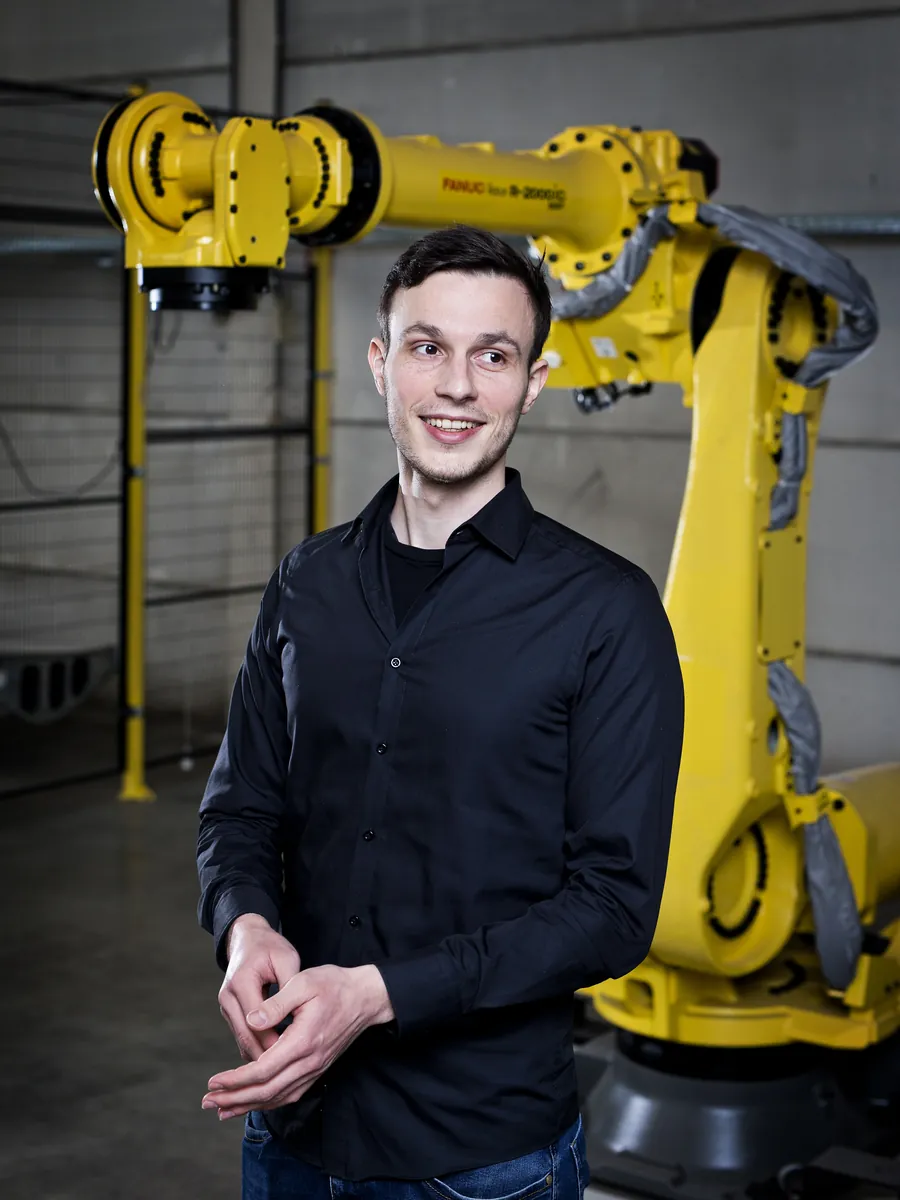 Jonas Rieder, oprichter van Eagle Creative, voor een gele industriële robotarm